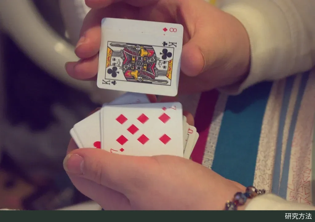 一双手正在洗一叠小号扑克牌,牌面上可见方块、黑桃花色和 K 牌