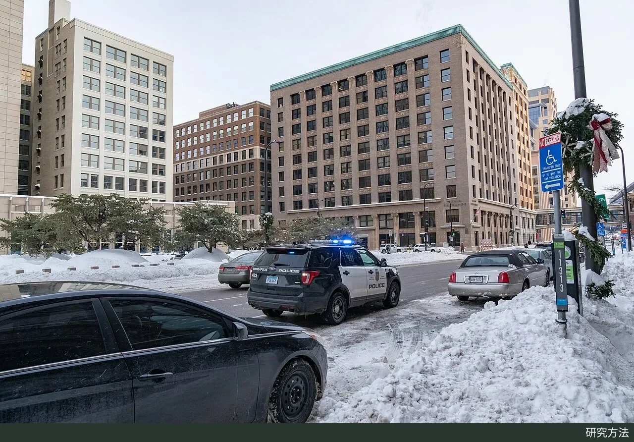 一辆明尼阿波利斯警察局巡逻车亮着警灯停在明尼阿波利斯市政厅门前，占用了一条车道